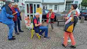 Die Teilnehmer des Senioren-Handycafés probieren aus, wie sie sich mithilfe ihres Smartphones Klappstühle auf dem Spittaplatz ausleihen können.