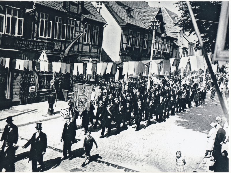 Foto 5 -  Schützenumzug in der Marktstraße. Links vor dem Haus des Kaufmanns Kosel (heute Drogeriemarkt Rossmann) die erste Tankstelle für Kraftfahrzeuge 1927